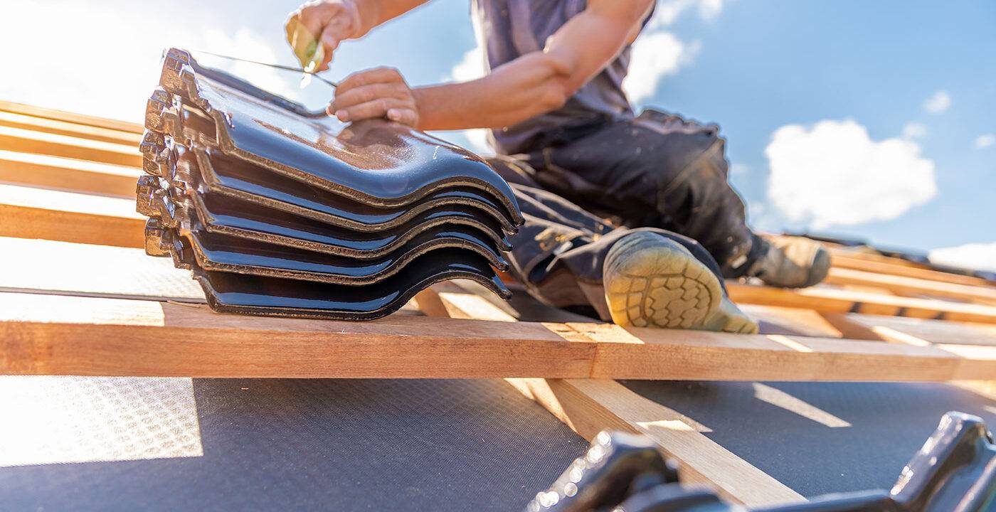 Close up of a roofer applying black ceramic shingles on a sunny day in Florida
